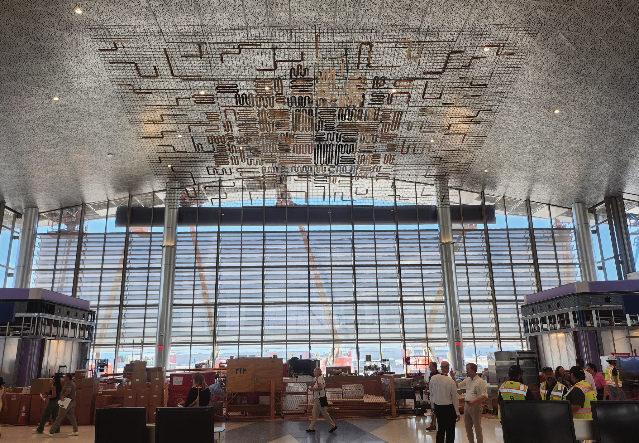 The main lobby under construction, with a suspended copper and metal art installation hanging from the ceiling